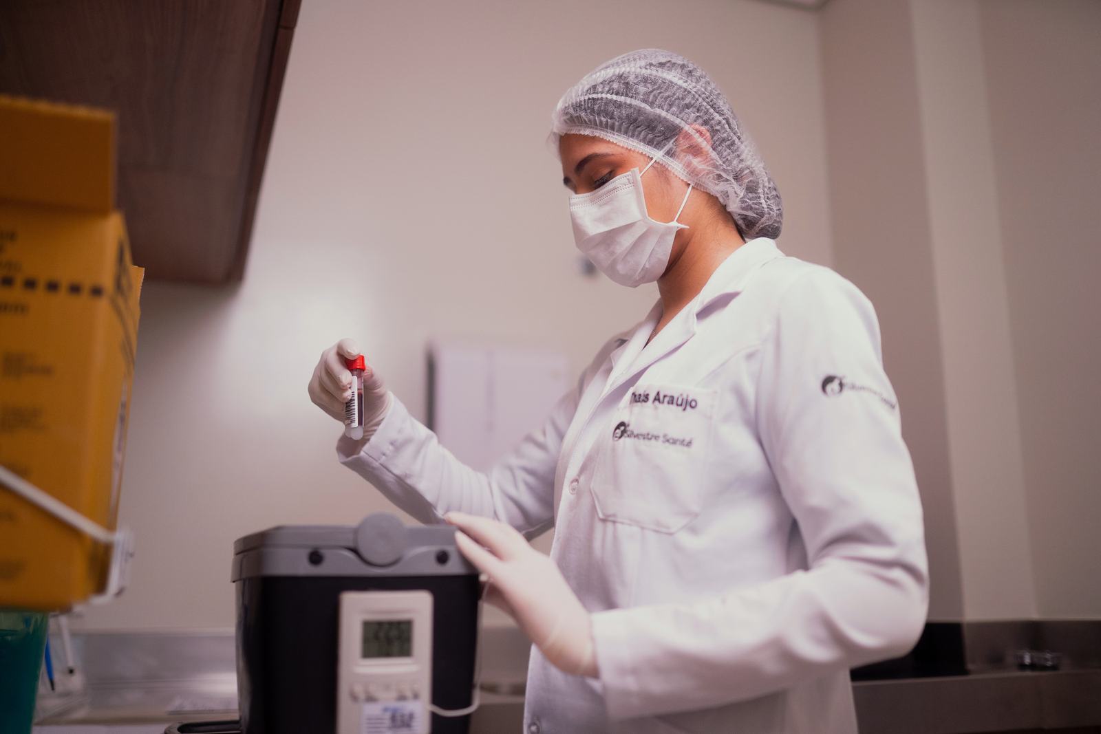 Biomédica manipulando tubo de amostra na sala de preparo